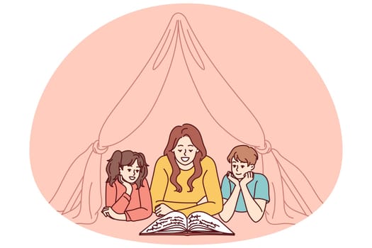 Nanny and two small children reading book lying on floor in tent enjoying fairy tale story. Mom spends time with pre-adolescent children and gets positive emotions from self-parenting