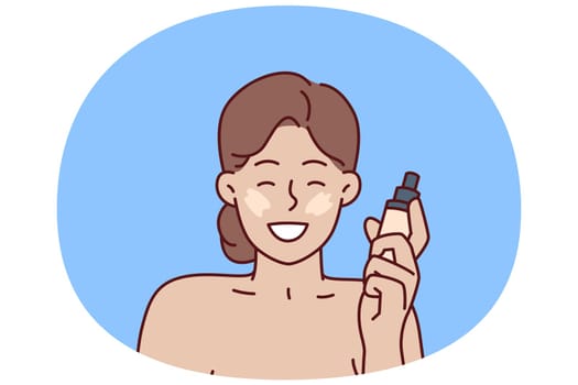 Woman with liquid foundation smiles as she puts on makeup to hide skin imperfections. Positive girl demonstrates new foundation recommending use of high-quality cosmetics for skin care