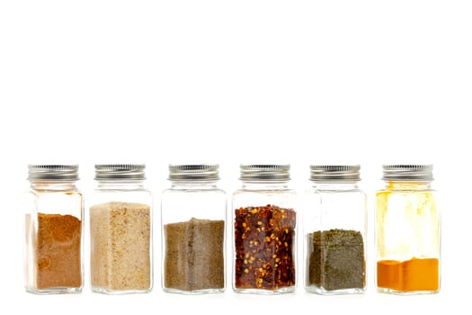 Square glass jars for storing dry kitchen spices. Selective focus with shallow depth of field.
