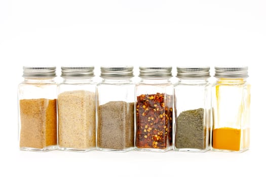 Square glass jars for storing dry kitchen spices. Selective focus with shallow depth of field.
