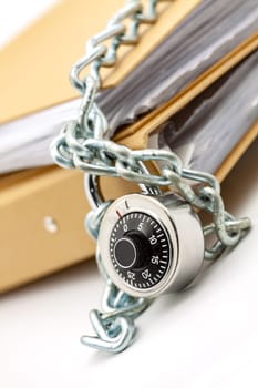Cardboard document folders locked with chain and padlock. Selective focus with shallow depth of field.