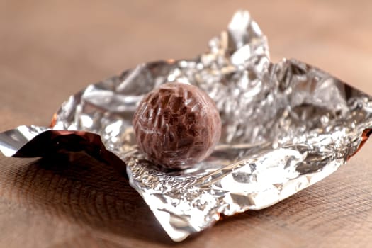 Chocolate candy developed on a foil packet on a wooden surface. Selective focus with shallow depth of field.