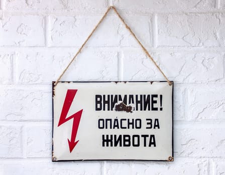 An old rusty enamelled Cyrillic sign warning of danger from an Eastern European country.