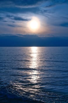 Sunset, illuminated sea. A few clouds in the sky, light waves rolling onto the Baltic Sea beach. Landscape on the coast