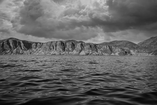 Norwegian fjord landscape. Mountains with rugged vegetation in black and white. Crystal clear water