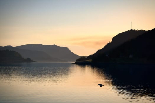 Norwegian fjord landscape with a view of the open sea at sunset. Water and mountains in the nature of Scandinavia