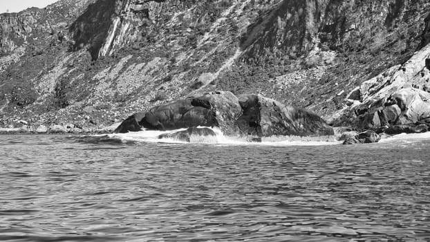 Norwegian fjord landscape. Waves crash against rocks in black and white. Water splashes against the rock. Landscape in Scandinavia