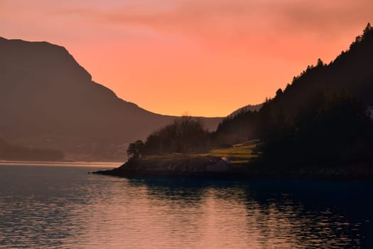 Norwegian fjord landscape with a view of the open sea at sunset. Water and mountains in the nature of Scandinavia
