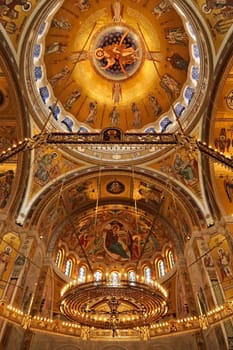 The interior of the Church of Saint, St. Sava, a big golden Chandelier in front of golden walls, vaults, domes, ceiling covered in mosaics, Belgrade, Serbia 2022