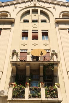 Beautiful balconies with green plants and an umbrella on the facade of a high neoclassical house, building close to the Knez Mihailova, Knez Mihaila Street in the city center of Belgrade, Serbia 2022