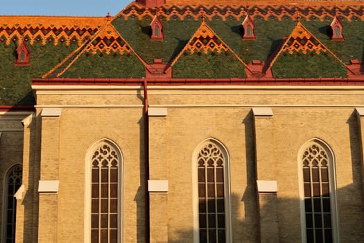 Side facade with stained glass windows and the colorful roof of the Name of Mary church in the city center, old town of Novi Sad, Serbia 2022