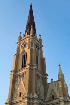 The bell, clock tower of the Name of Mary Church with its colorful roof in front of a blue sky, Novi Sad, Serbia 2022
