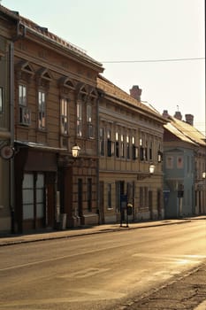 Golden hour inside the Petrovaradin Lower Fortress, sunlight is shining through the street lamps, lanterns on the facades of historic buildings and reflecting on the windows, Novi Sad, Serbia 2022