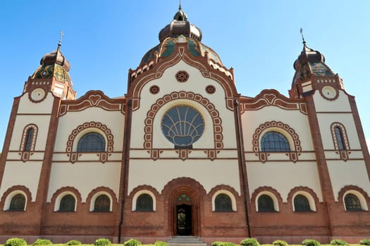 The complete facade around the side entrance of the Synagogue of Subotica on a sunny day with blue sky and white clouds, Subotica, Serbia 2022