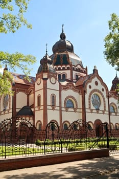 The Synagogue of Subotica behind a black metal fence with elaborate details on a sunny day, Subotica, Serbia 2022