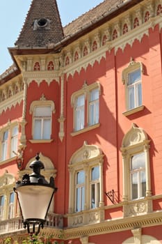 The facade of the Vojnic Palace building with a bay window, tower and a street light, lamp, lantern in the foreground, city center of Subotica, Serbia 2022