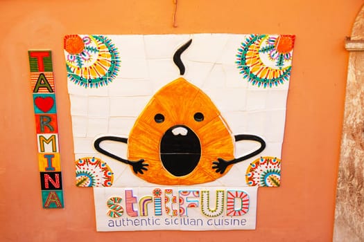 Sicily, Taormina, Italy - 28 Sep 2023. Ceramic advertisement on a wall for a street food (Strit Fud) restaurant in Via di Giovanni in centre of Taormina.