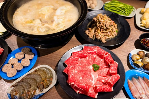 Hot pot with lots of food on the table