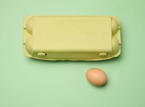 Chicken egg and paper storage box on green background, top view