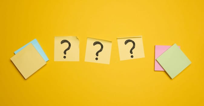 Drawn question marks on stickers, yellow background. Searching for truth and answering questions