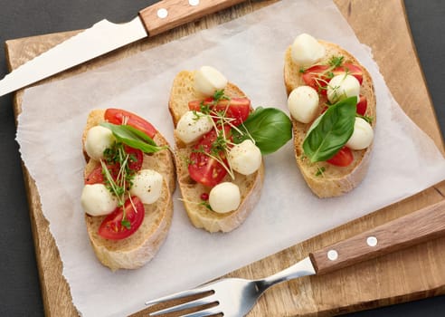 Round mozzarella, cherry tomatoes and microgreens on a piece of white bread, a healthy sandwich