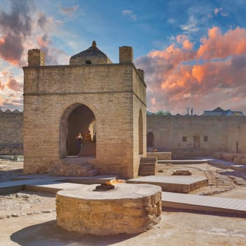 Baku, Azerbaijan - May 9, 2024: A view of the Ateshgah Fire Temple. The temple is lit by the setting sun, and a fire burns in the foreground