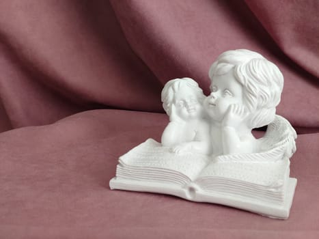 Background image of a statuette of little angels reading a book.Texture or background.