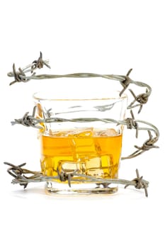 Barbed wire around glass with ice and alcohol on white background