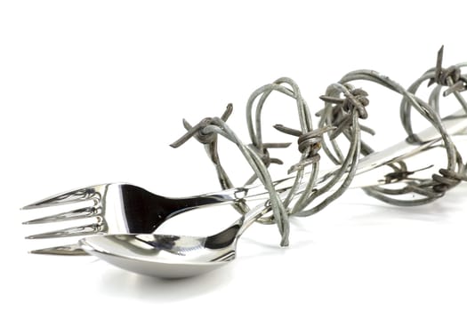 Barbed wire around fork and spoon on white background