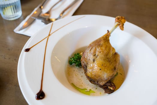 Duck leg confit on white dish