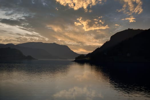 Norwegian fjord landscape with a view of the open sea at sunset. Water and mountains in the nature of Scandinavia
