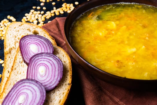 Homemade healthy vegetable soup with some bread and an onion