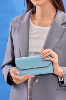 Women's hands hold a blue handbag. High quality photo