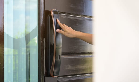 Female hand opening a door with fingerprint scanning of smart digital electronic door lock at home or apartment. Security keyless access control concept.