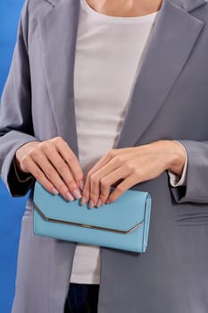Women's hands hold a blue handbag. High quality photo