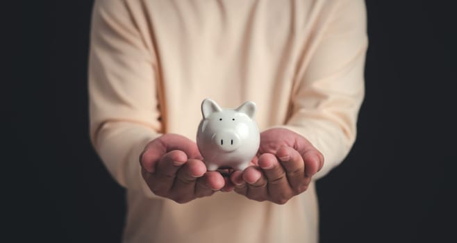 A man holding the white piggy bank for saving money concept, Money saving concept, Save for investment, banking, loan, home loan, Financial planning, education and healthy insurance.
