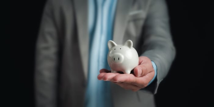 Businessman holding the white piggy bank for saving money concept, Money saving concept, Save for investment, banking, loan, home loan, Financial planning, education and healthy insurance.