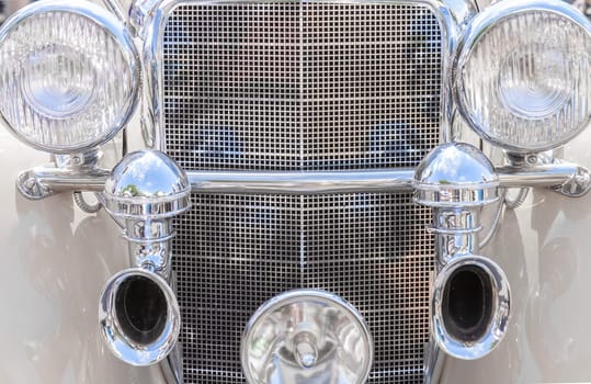 Details of the radiator grille and the headlights of a vintage car