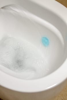 Modern toilet bowl with blue detergent for cleaning and disinfection