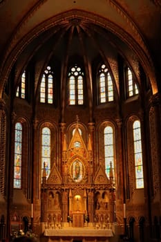 Elaborate altar in front of stained glass windows in gothic style shape inside the Matthias Church, Budapest, Hungary 2022