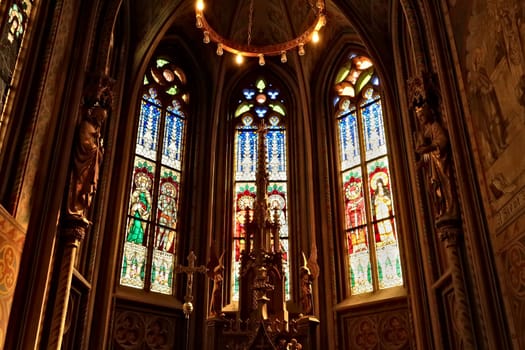 Small altar in front of colorful stained glass windows in gothic style shape inside the Matthias Church, Budapest, Hungary 2022