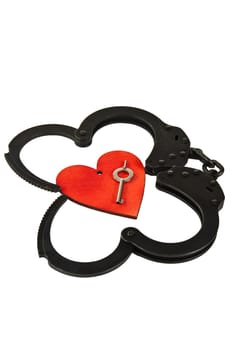 Black oxide handcuffs and red wooden heart on a white background