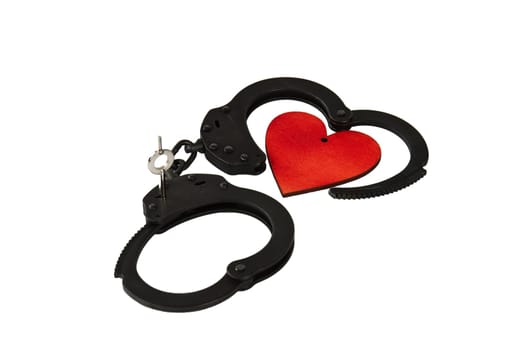 Black oxide handcuffs and red wooden heart on a white background