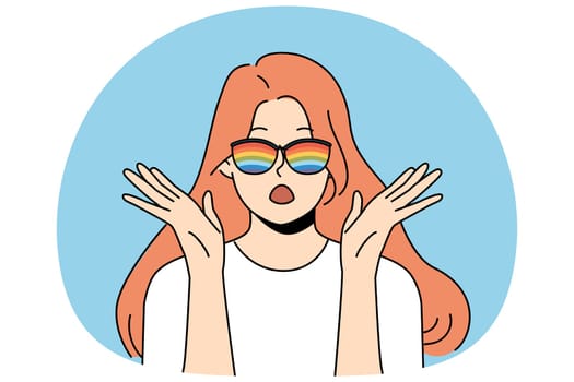Woman with rainbow glasses exclaims loudly and makes gesture of surprise when sees unusual phenomenon or hears exciting news. Shocked girl in sunglasses with rainbow stripes looks at screen