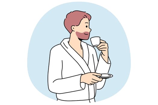 Man in bathrobe drinks coffee enjoying hot tart drink after waking up in morning. Successful young man with tea having rest in hotel or using services of spa center during vacation or weekend