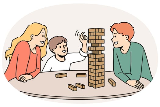 Happy family plays jenga with child enjoying board game and developing fine motor skills in baby. Satisfied boy plays jenga with parents pulling wooden block out of unstable tower.