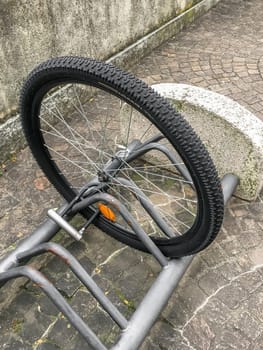 A damaged bike wheel is all that is left of a bicycle chained to a bike stand. Stolen bicycle. Chained bicycle wheel.