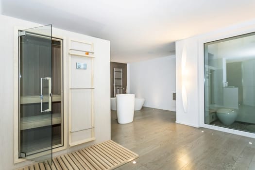 Bathroom of modern luxury house. Wooden floor. Modern sauna interior with glass door.