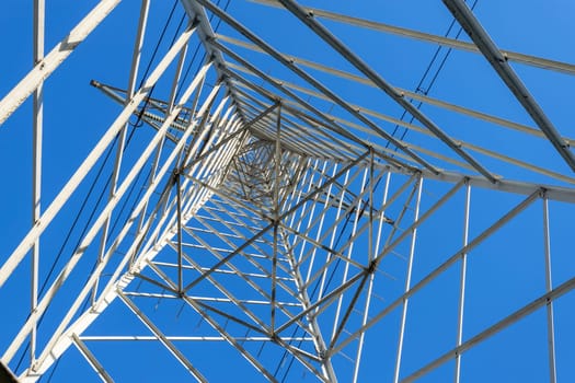 High Voltage Electricity Grid Pylon seen from below and blue sky