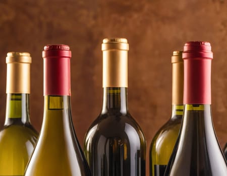 Close-up of assorted wine bottles with red and gold caps, arranged against a brown background.
